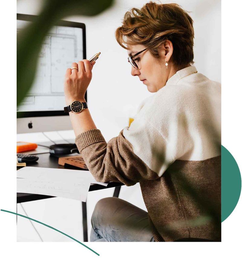 A woman sitting at a desk with a pen in hand.